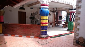Um pátio com piso de azulejos, um banco de tijolos e pilares coloridos.