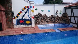 Uma piscina com parede de mosaico com desenhos de peixes e uma estrela.