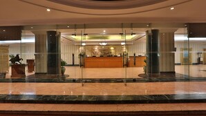 A lobby with a reception desk, glass partitions, and a marble floor. - Aryaduta Suites Semanggi (Jakarta)