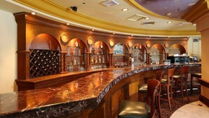 A bar area with a curved marble countertop, wooden bar stools, and a wine rack. - Aryaduta Suites Semanggi (Jakarta)