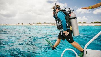 A person in scuba gear stepping off a boat onto a clear blue sea.
