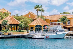 A waterfront property with a boat dock, a covered area with a palm tree, and a building with a tiled roof. - Harbour Village Beach Club Bonaire (Kralendijk)