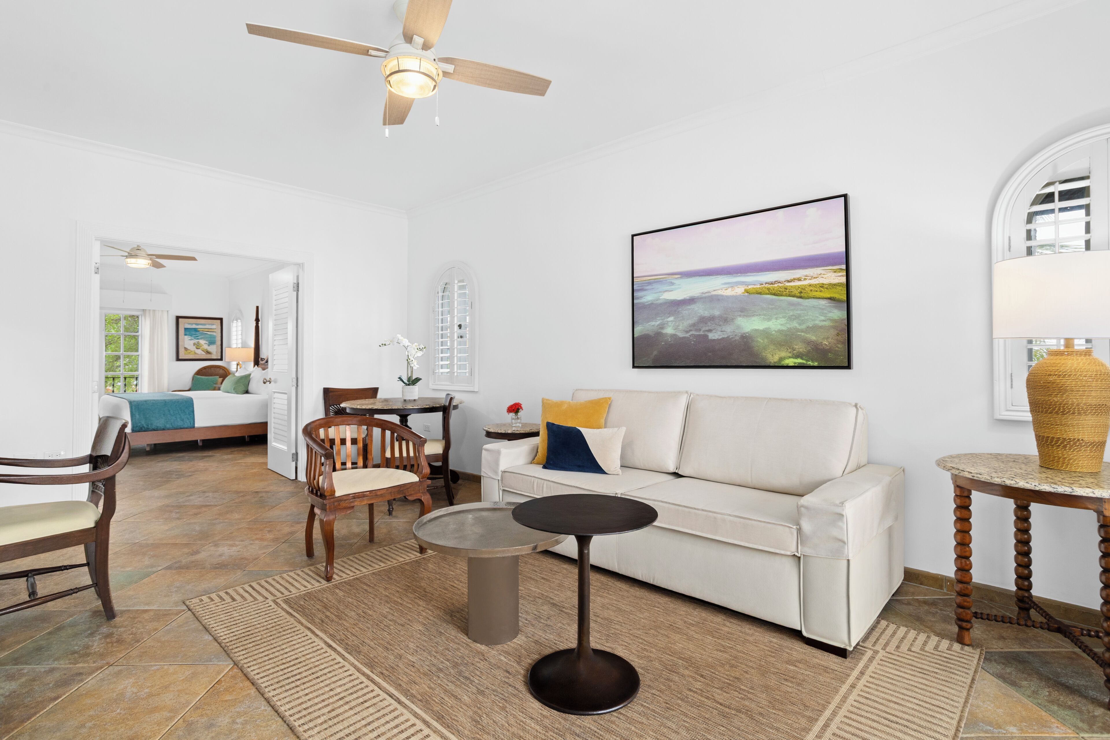 A living room with a white sofa, a round coffee table, and a ceiling fan.