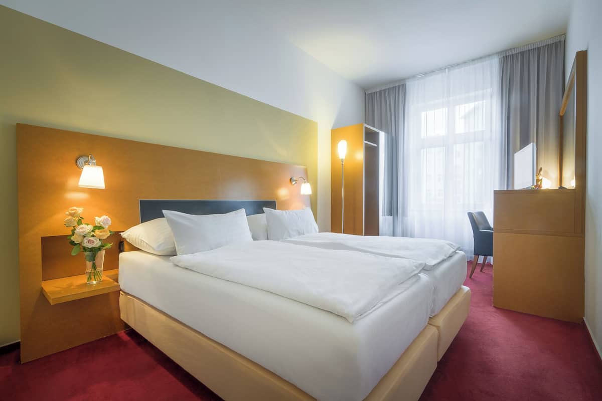 Een hotelkamer met een groot bed, nachtlampen, een bureau en een spiegel.