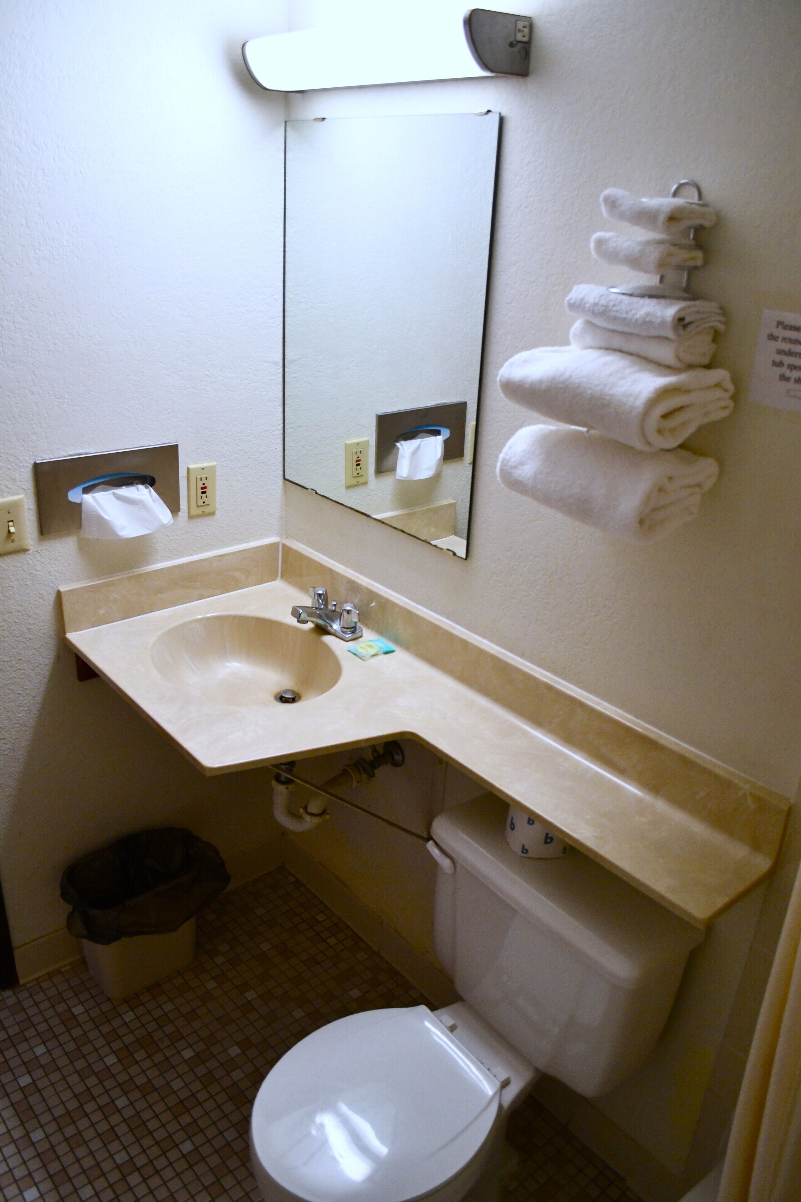 A bathroom with a sink, mirror, toilet, and a towel rack.
