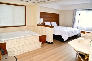 Una habitación de hotel moderna con una cama grande, un baño separado con bañera y lavamanos.