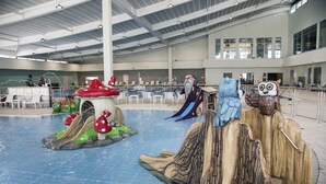 Una piscina interior con toboganes y formaciones rocosas artificiales.