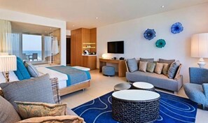 A modern hotel room with a bed, sofa, and armchair, a desk, and a TV. - Nachsholim Holiday Village Hotel (Hof HaCarmel)