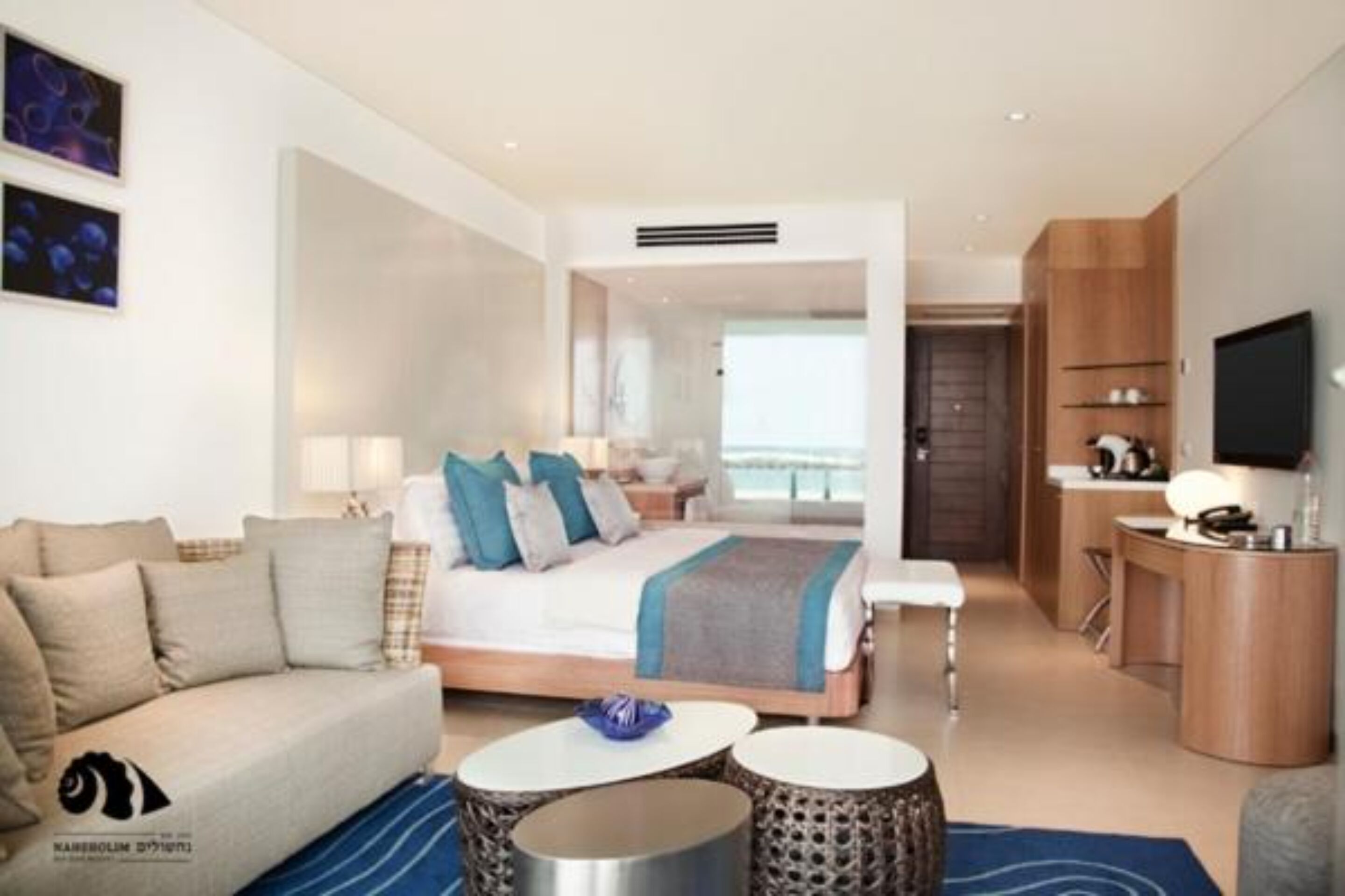 Ett modernt hotellrum med en säng, en soffa, ett skrivbord och en tv.
