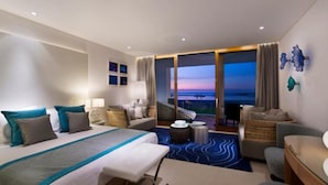 Una habitación de hotel con una cama grande, una zona de estar con vistas y un balcón.