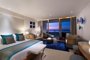 Una habitación de hotel con una cama grande, una zona de estar con vistas y un balcón.