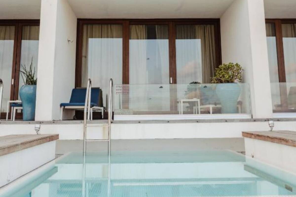 A hotel with a pool, two balconies, and a seating area with chairs and a table.