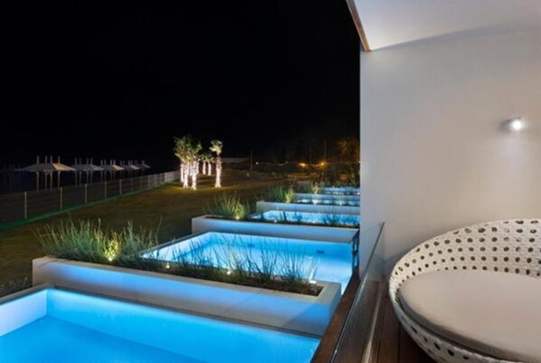 A pool area with multiple rectangular pools, each surrounded by plants and illuminated by blue lighting.