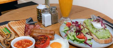 Prato de café da manhã com ovos, bacon, torradas e uma salada.