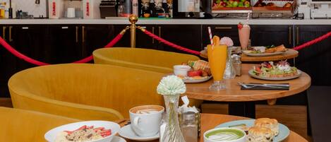 A dining area with a round table set for breakfast, including plates of food, a coffee cup, and a vase with flowers.