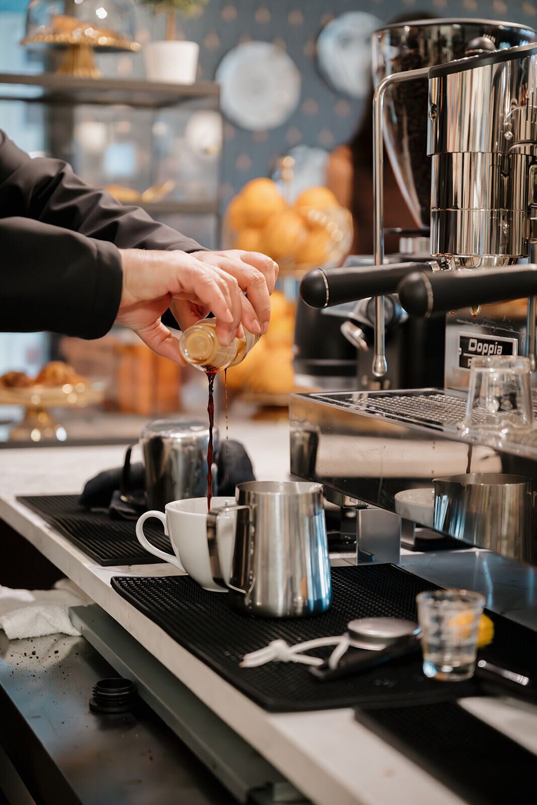 A barista preparing a drink at a coffee machine.