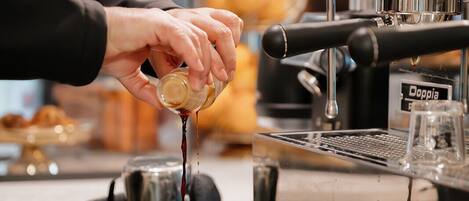 Eine Barista bereitet ein Getränk an einer Kaffeemaschine zu.