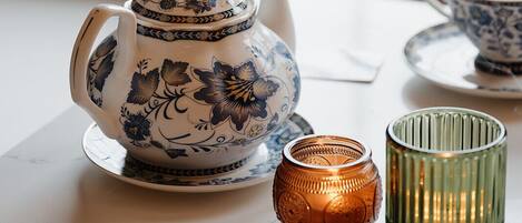 Una mesa con una tetera, tazas y una vela.
