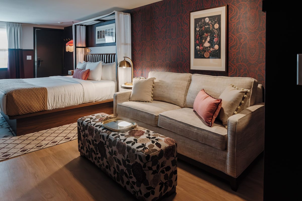 Una habitación de hotel con cama, sofá, mesita de café y pared decorada.