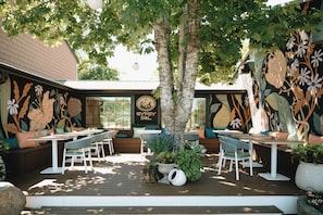 Un espace extérieur aménagé avec des tables et des chaises, entouré de murs décoratifs et de plantes.