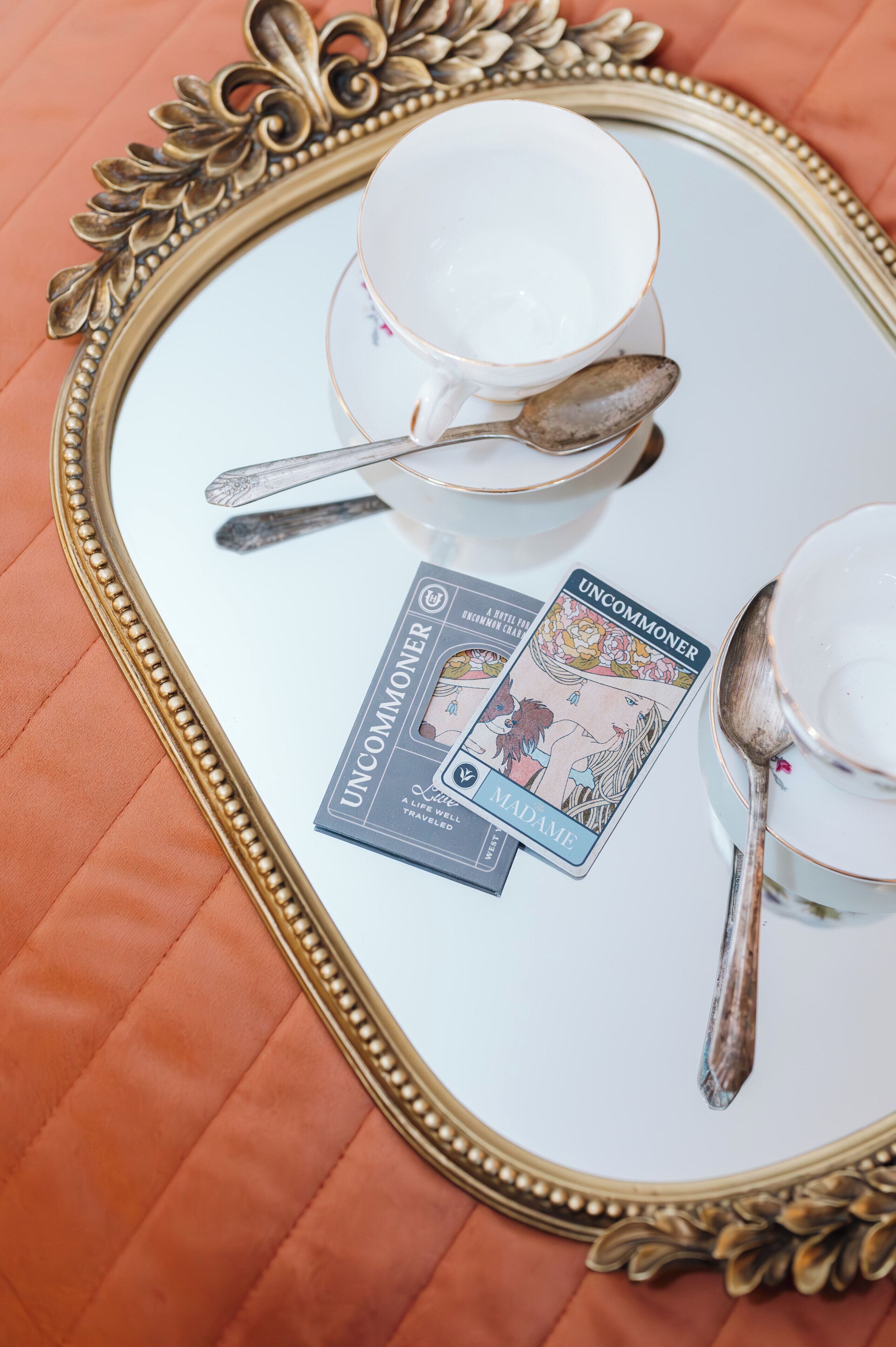 Un plateau sur lequel se trouvent une tasse, une soucoupe, une cuillère et des cartes de tarot, le tout posé sur une surface réfléchissante.