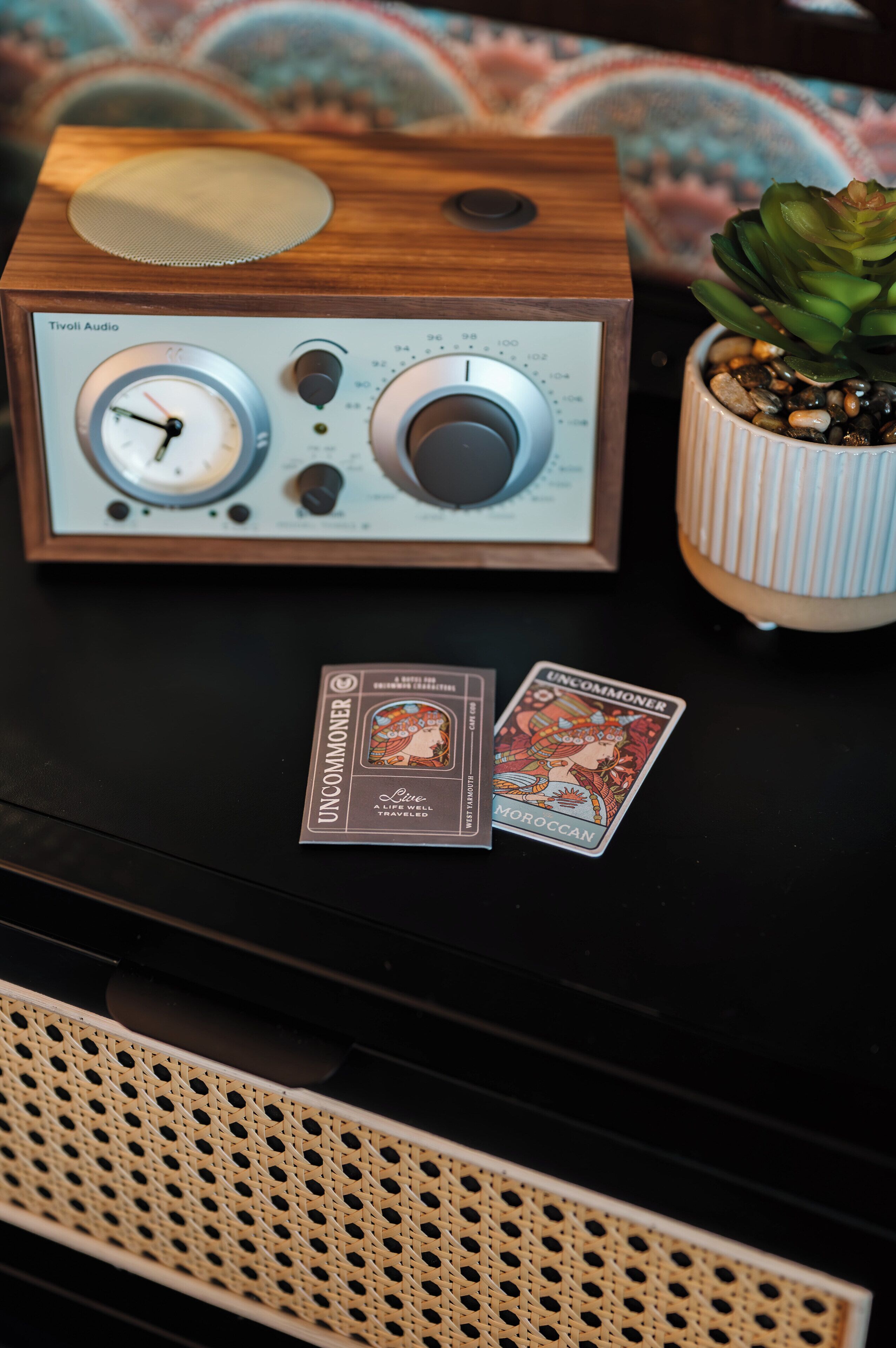 A wooden radio with tuning dials and a small card labeled "Uncommoner" on a black surface.