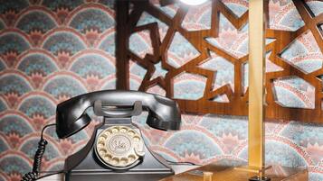 Un telefono rotativo vintage su un tavolo rotondo, con una lampada dorata e un libro.