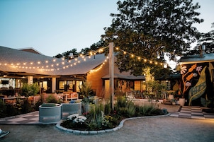Un restaurante con terraza, luces colgantes y una pared decorativa.