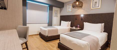 A hotel room with two beds, a desk, and a chair.