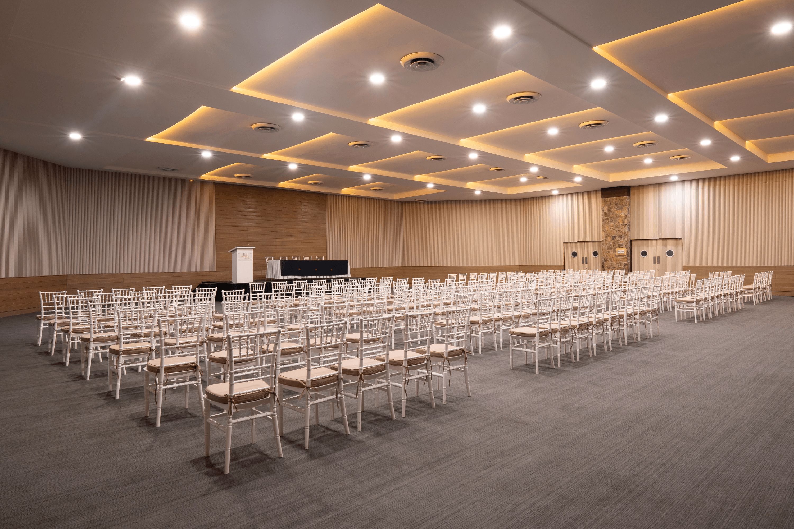 Un salón de conferencias con filas de sillas, un atril y un escenario.