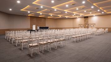 Un salón de conferencias con filas de sillas, un atril y un escenario.