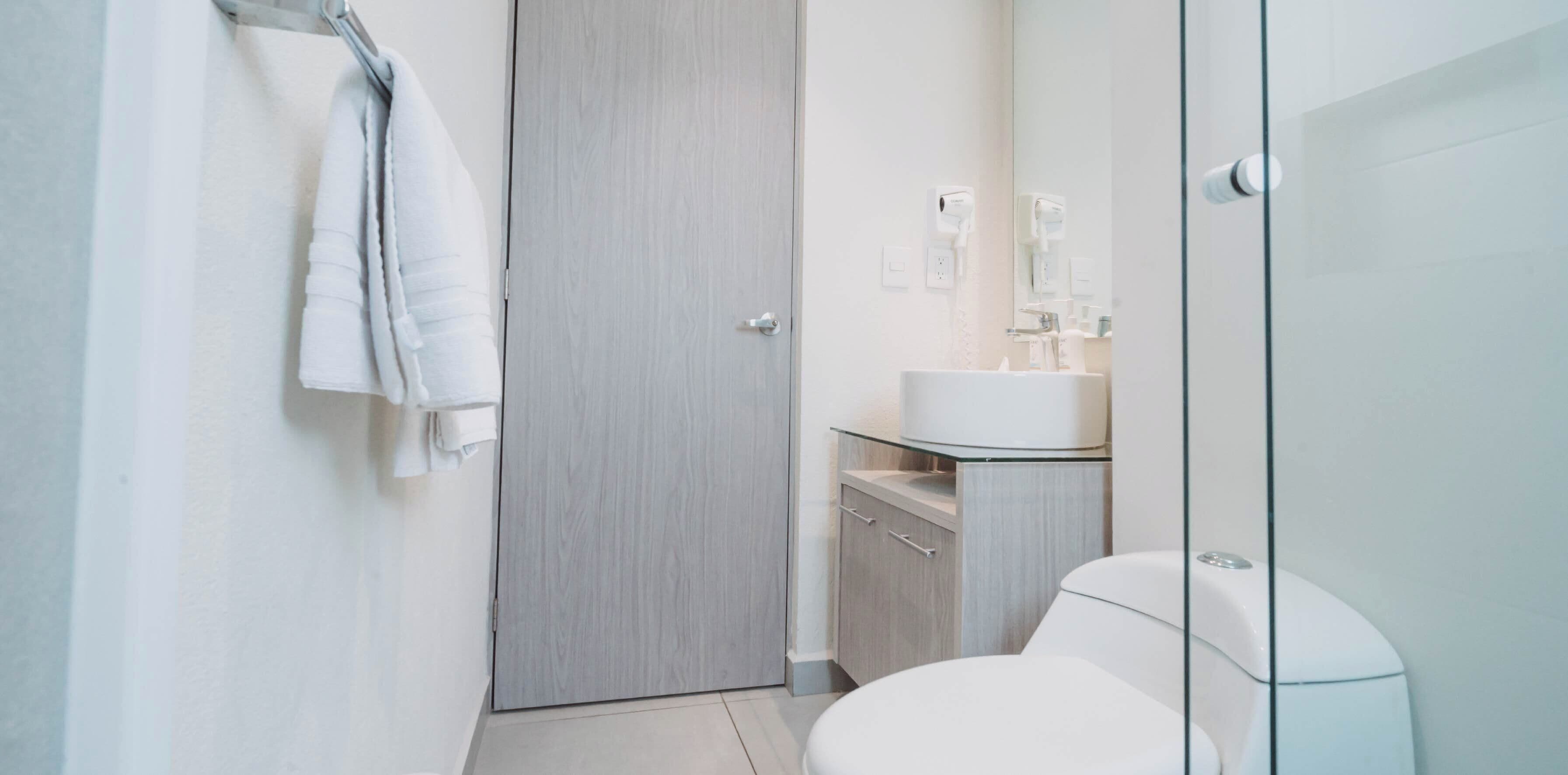 Ein modernes Badezimmer mit Toilette, einer Duschkabine aus Glas und einem hölzernen Waschtisch.