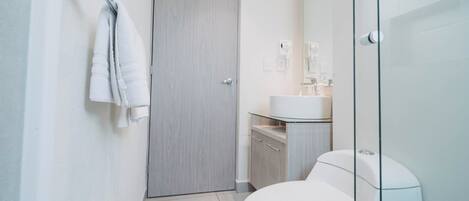Ein modernes Badezimmer mit Toilette, einer Duschkabine aus Glas und einem hölzernen Waschtisch.