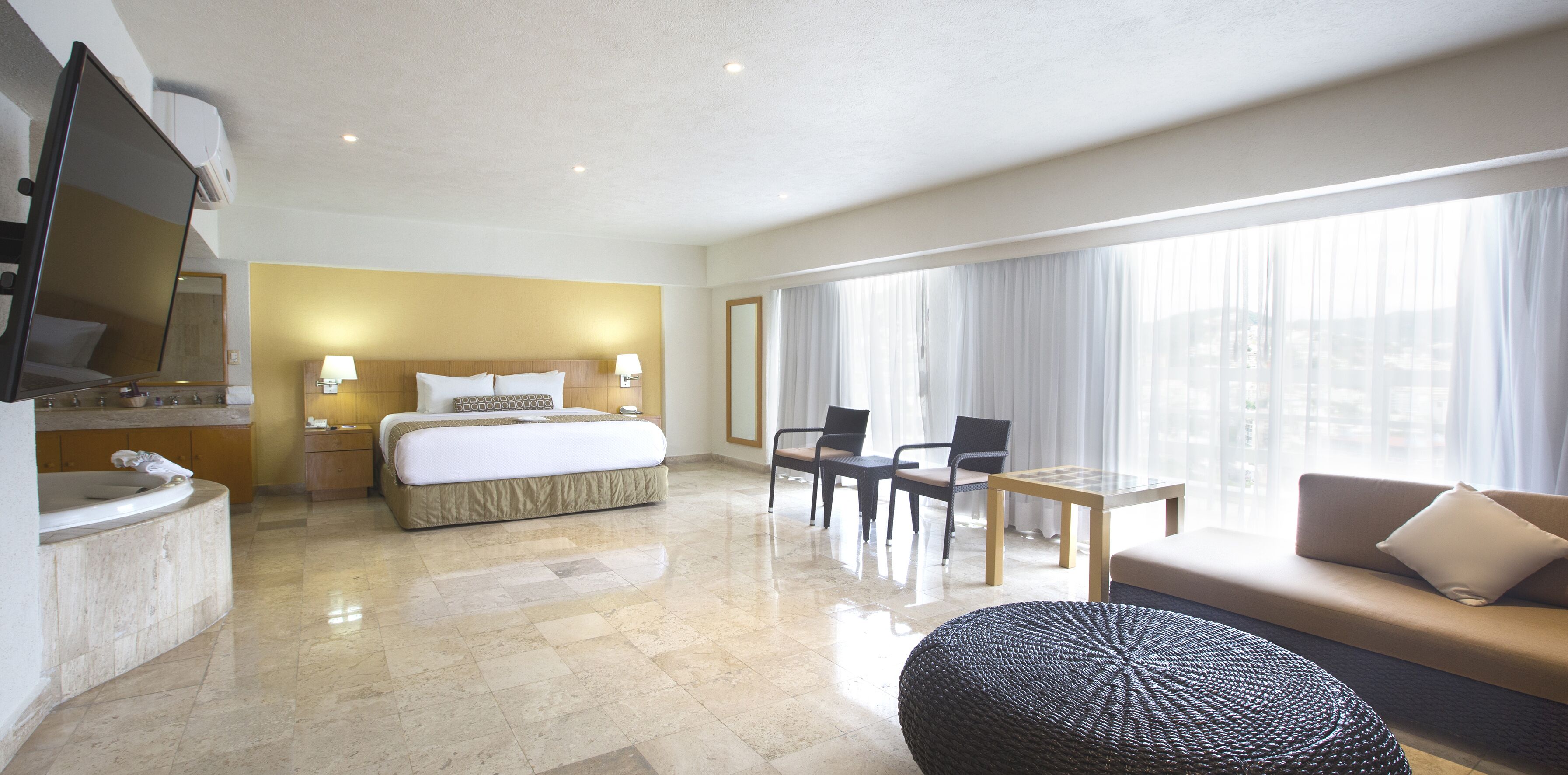 A hotel room with a bed, a desk, a sofa, and a TV.