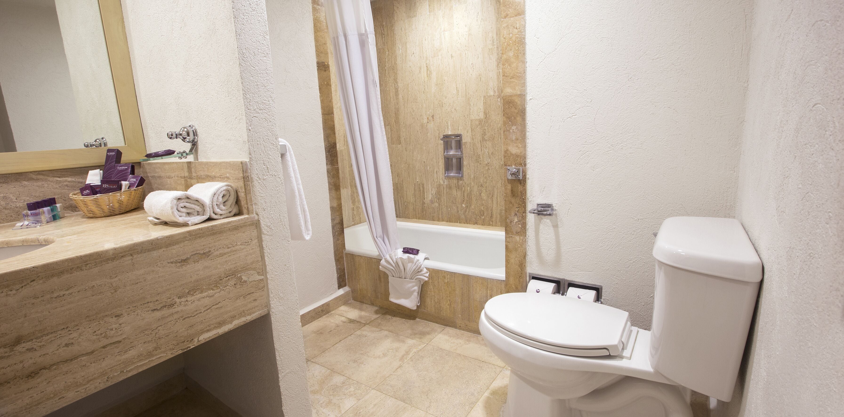 A bathroom with a bathtub, toilet, and a vanity with a mirror.