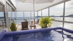 Un balcón con vista al mar, una piscina pequeña y mobiliario exterior.