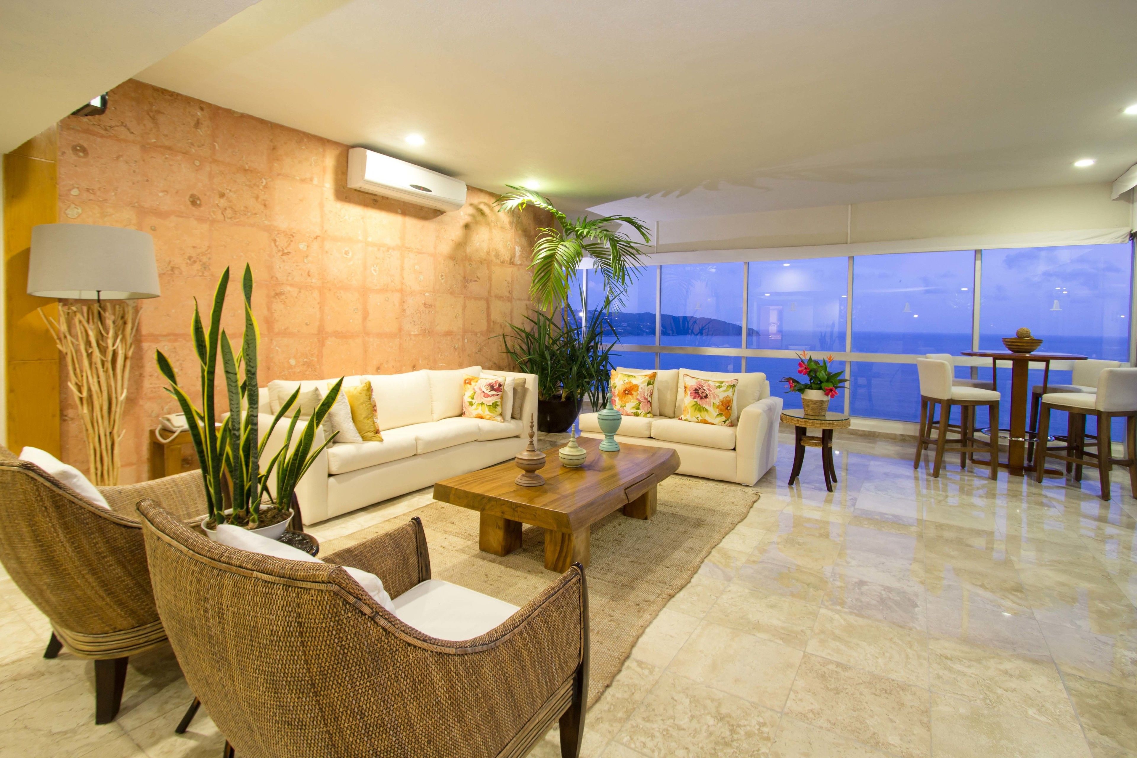 A modern living room with a sofa, chairs, a coffee table, and a view of the ocean.
