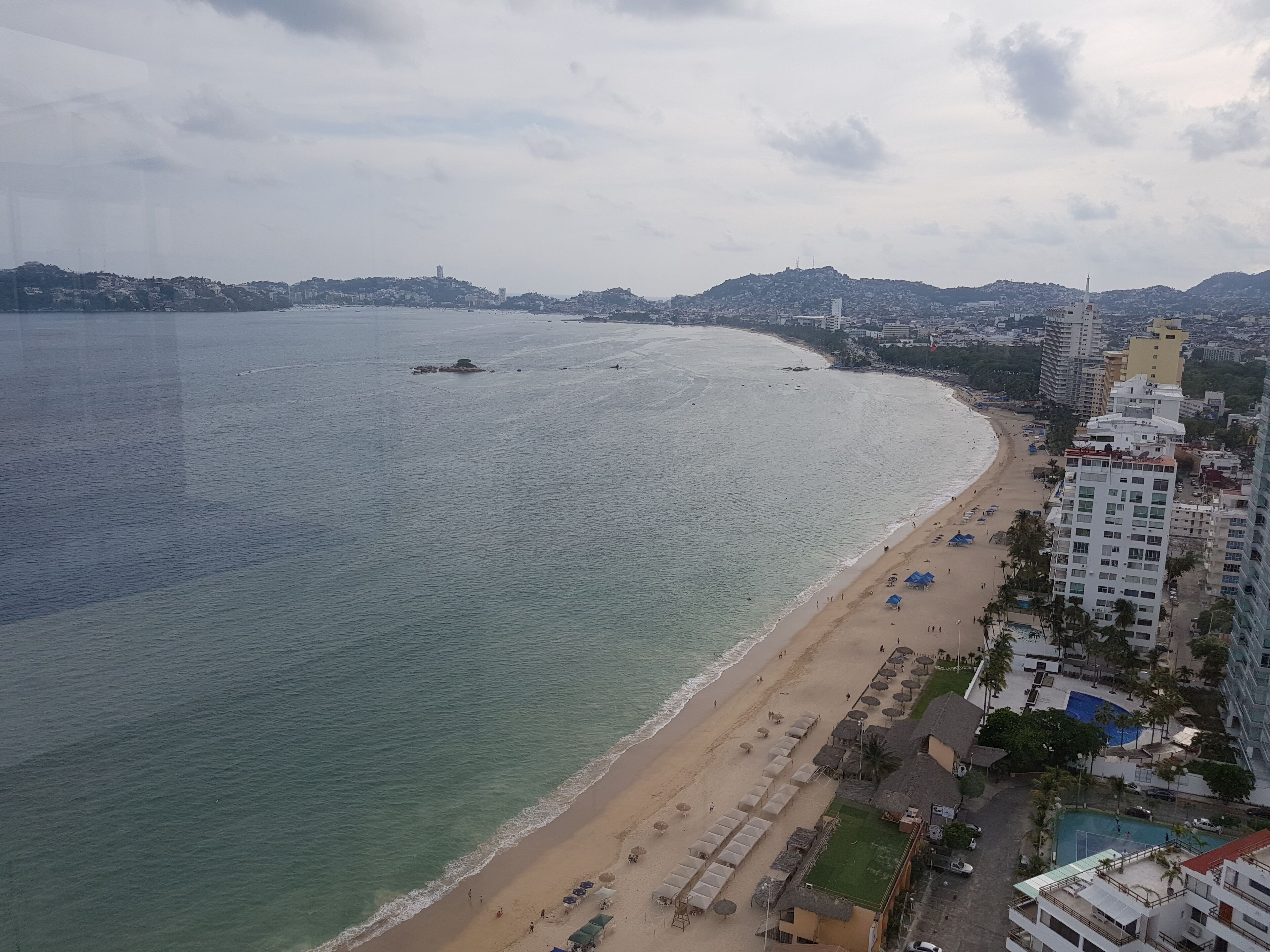 Paisatge urbà costaner amb una platja, edificis alts i un cel serè.