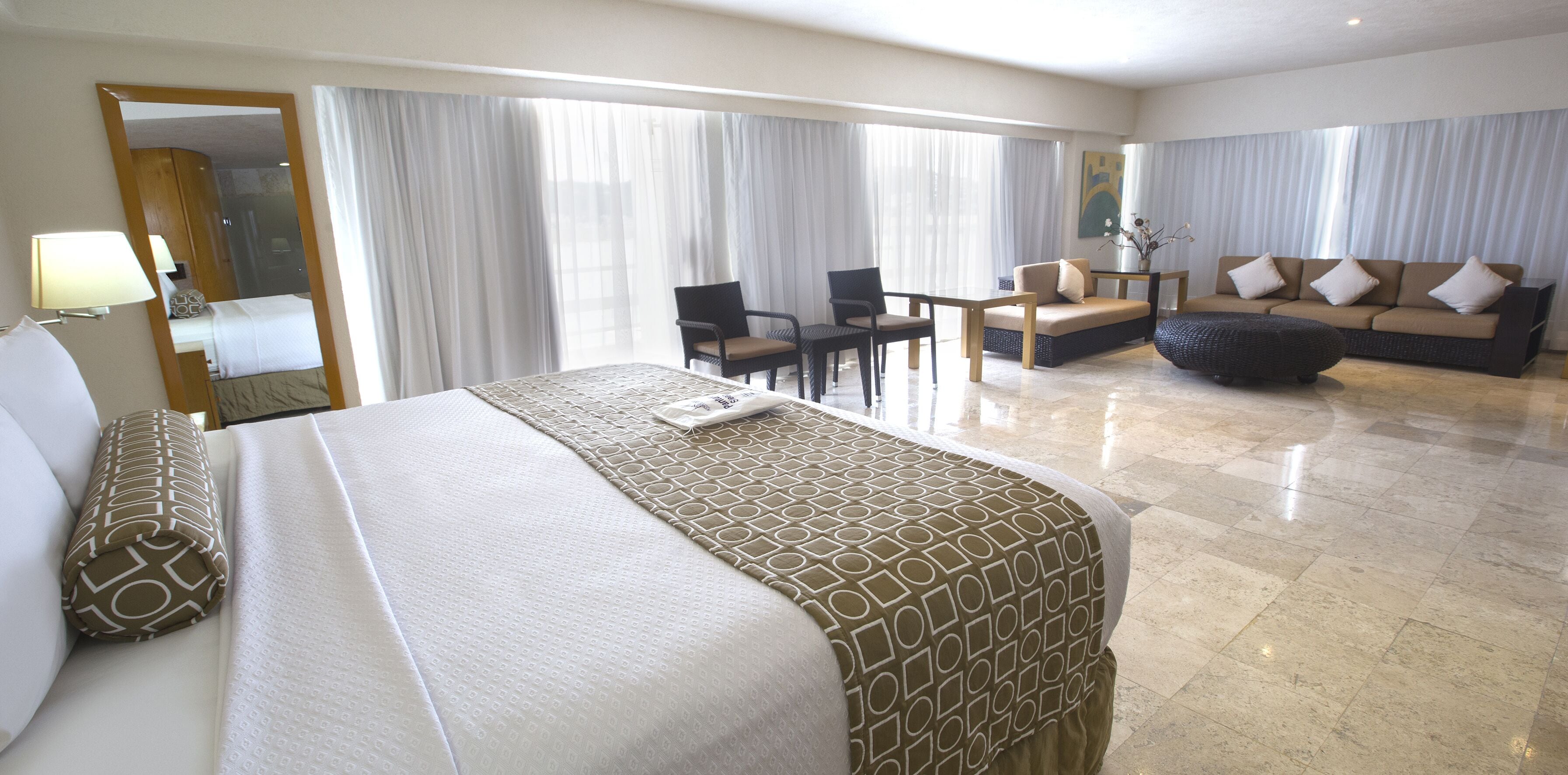 Een hotelkamer met een groot bed, een bank, een eettafel en een stoel.