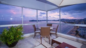 Un balcón con vista a la playa y al paisaje urbano al anochecer.