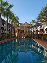 Una piscina rodeada por un edificio con varios balcones y palmeras.