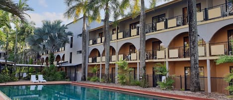 Un hotel con varios balcones, piscina y palmeras.
