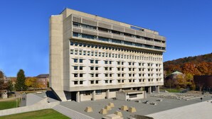 Un edificio moderno con fachada de entramado, varios balcones y un amplio patio con esculturas geométricas.
