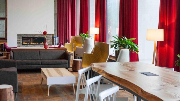Una sala de estar moderna con chimenea, cortinas rojas y una mesa de comedor de madera.