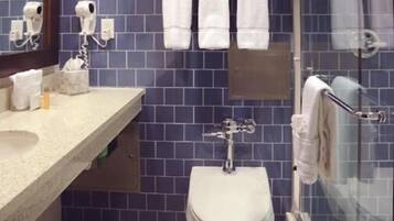 A bathroom with a toilet, sink, and a glass shower enclosure.