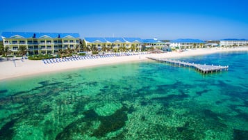 Een resort met een strand, helder water en een steiger.