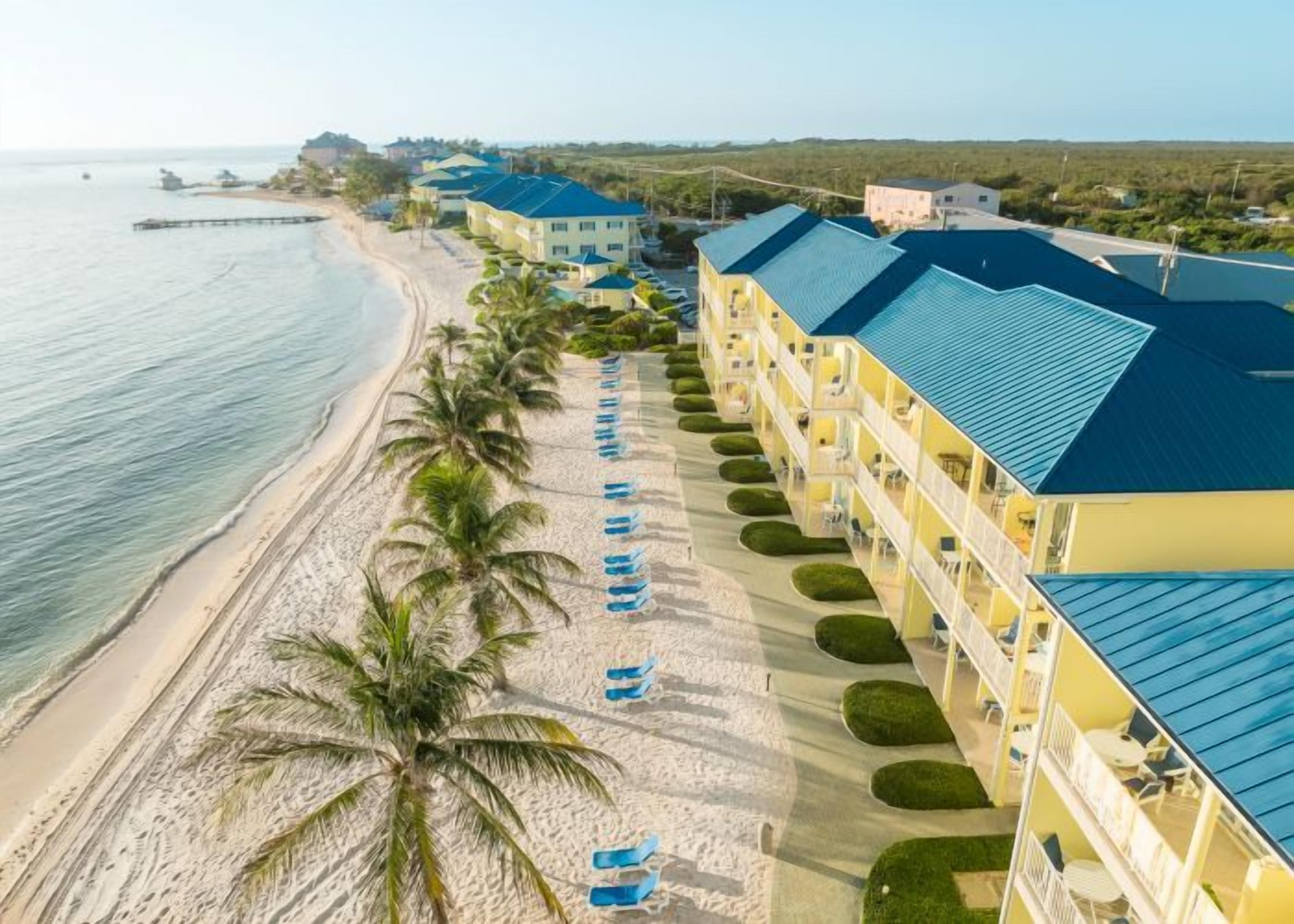 A beachfront hotel with multiple balconies, a sandy beach, and a clear view of the ocean.