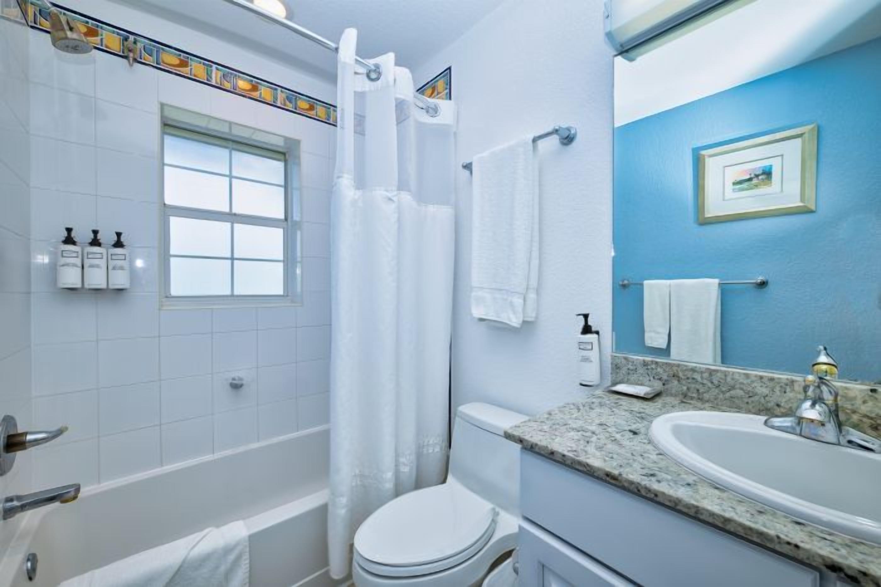 Un baño con bañera, inodoro, lavabo y cortina de ducha.