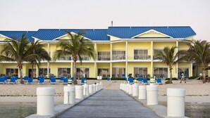 A hotel with a blue roof, multiple balconies, and a beachside location. - The Reef Beach Resort, East End, Grand Cayman (East End)