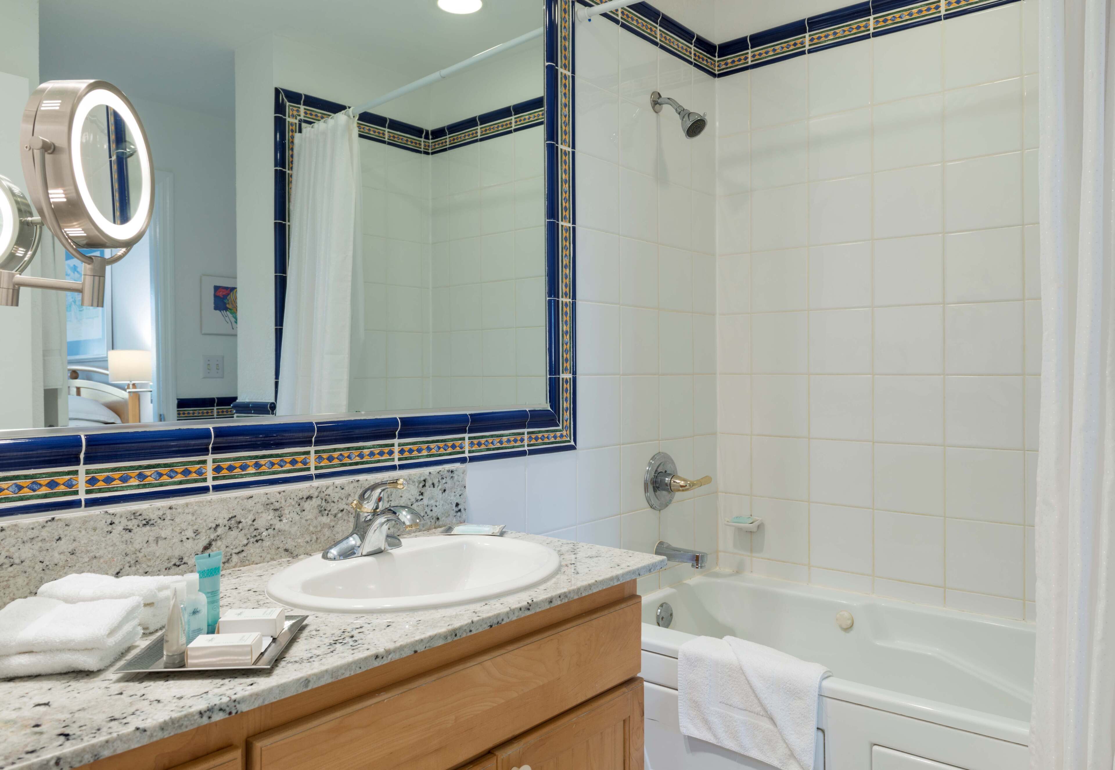 A bathroom with a sink, mirror, and shower.